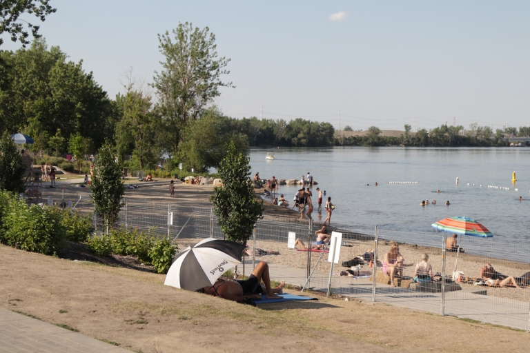 Plage ensoleillée avec des personnes hors de l'eau et d'autres dans l'eau.