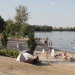 Plage ensoleillée avec des personnes hors de l'eau et d'autres dans l'eau.